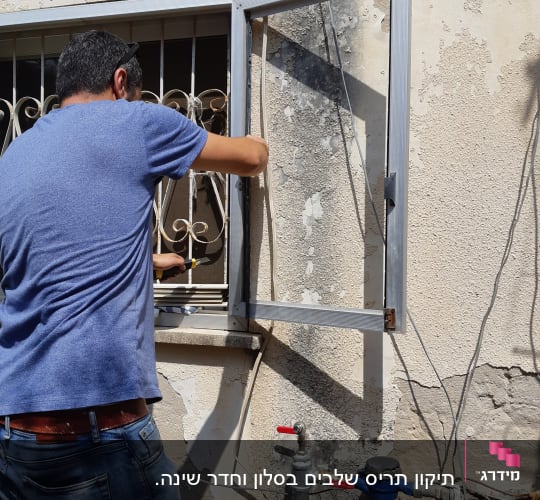 אדם מתקין תריסים על חלון עם מסגרת מתכת